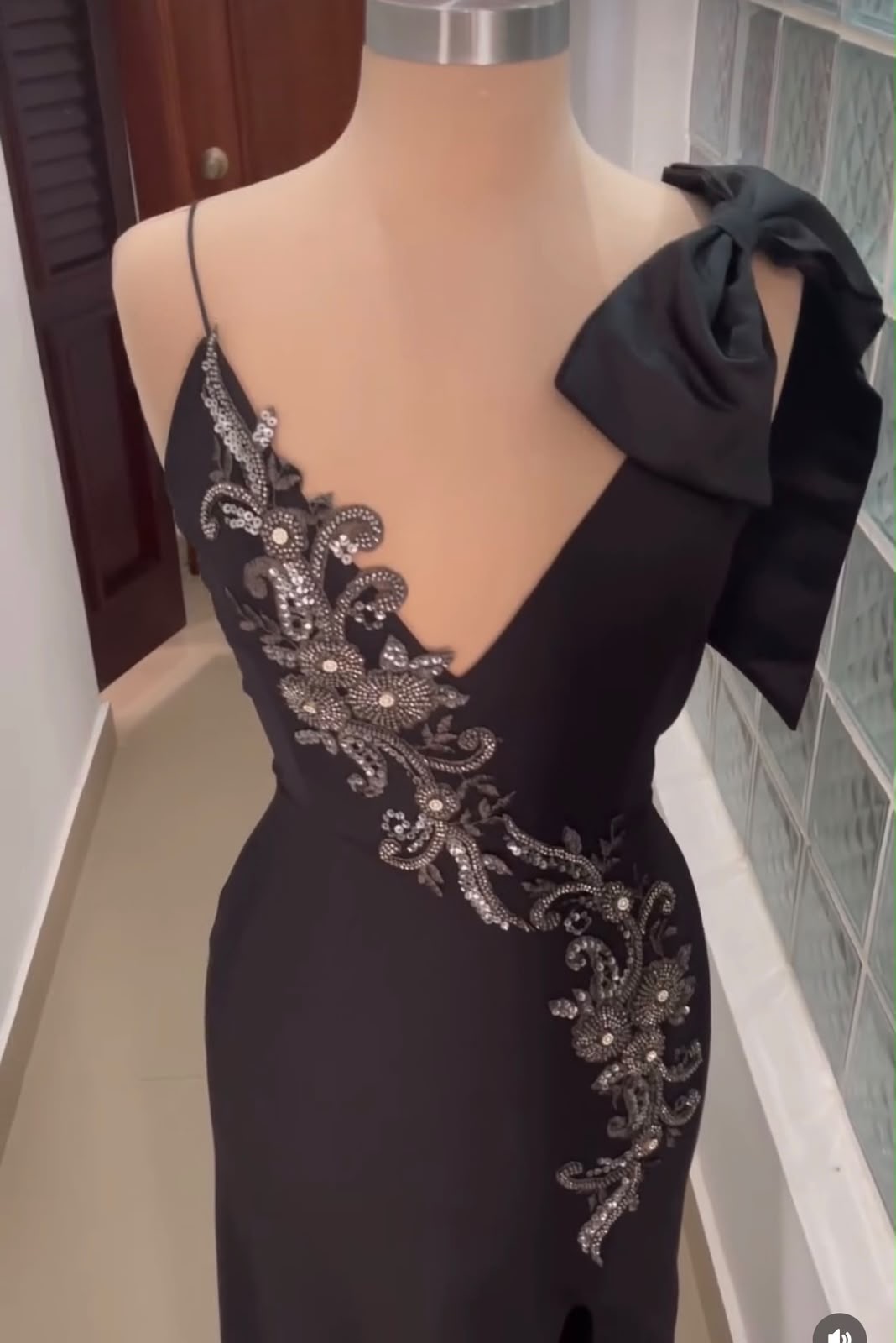 Vestido de gala negro con detalles plateados y moño en el hombro